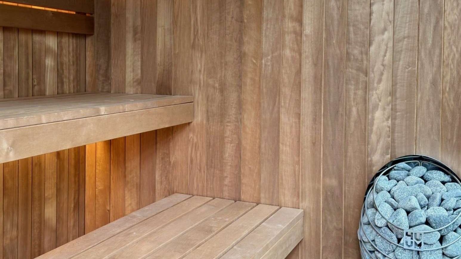 NORD Cube 240 interior — knot-free thermo aspen walls, floating benches and HUUM heater with stones